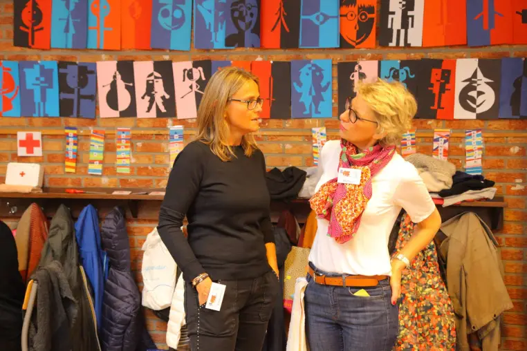 Deux femmes devant une fresque murale aux motifs colorés.