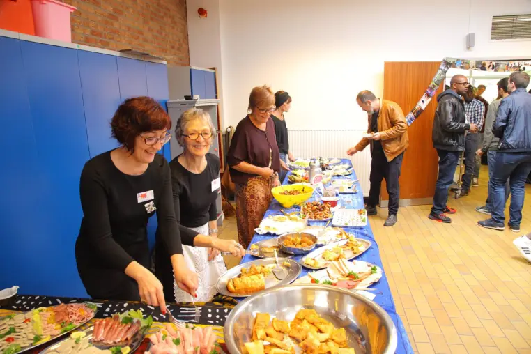 Deux femmes disposent les plats sur la table du buffet.