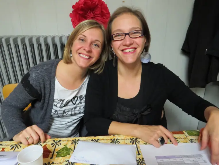 Deux femmes accueillent les visiteurs derrière une table couverte de documents.