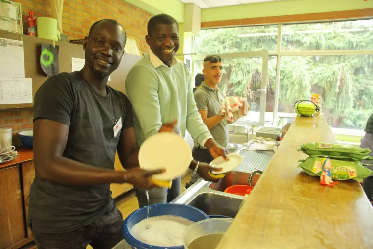 Deux hommes présentent un plat qu'ils viennent de préparer en cuisine.