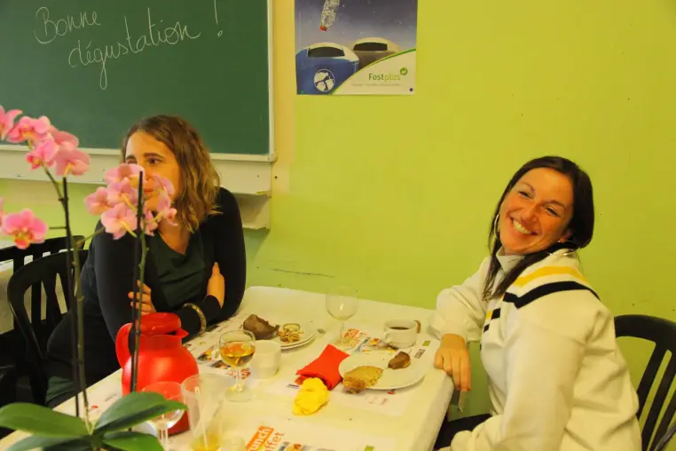 Deux femmes attablées devant un tableau où est écrit « Bonne dégustation ».