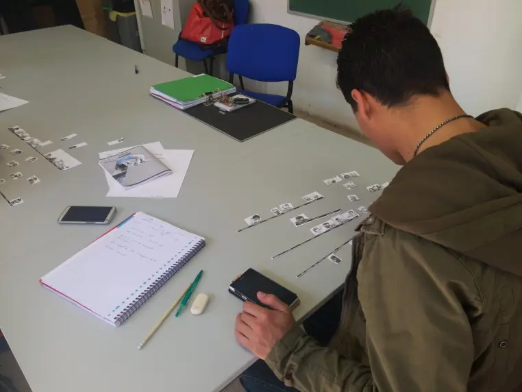 Un participant prend des notes lors d'un atelier, cahier et documents devant lui.