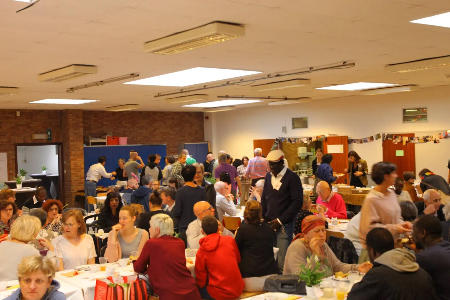 Une grande salle où de nombreux convives partagent un repas.