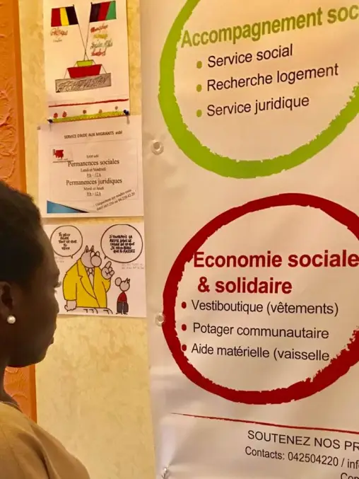 Une feme lit un panneau qui présente l'accompagnement social et l'économie sociale.