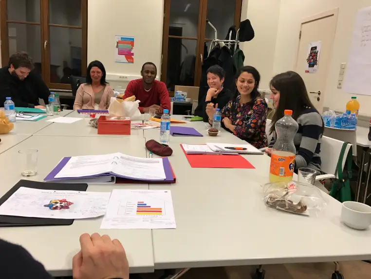 Une réunion de travail autour d'une grande table, dossiers ouverts.