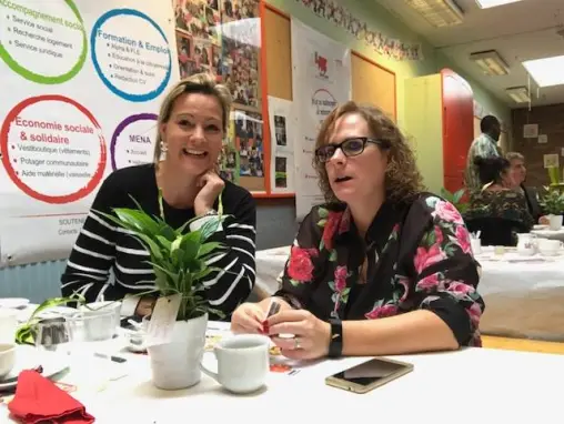 Deux femmes tiennent le stand de l'association, devant ses panneaux.