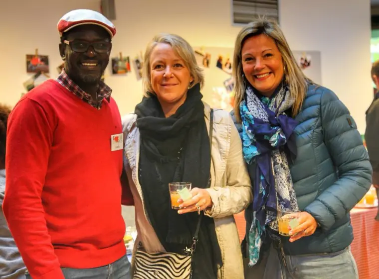 Trois personnes discutent, un verre à la main, lors d'un moment convivial.