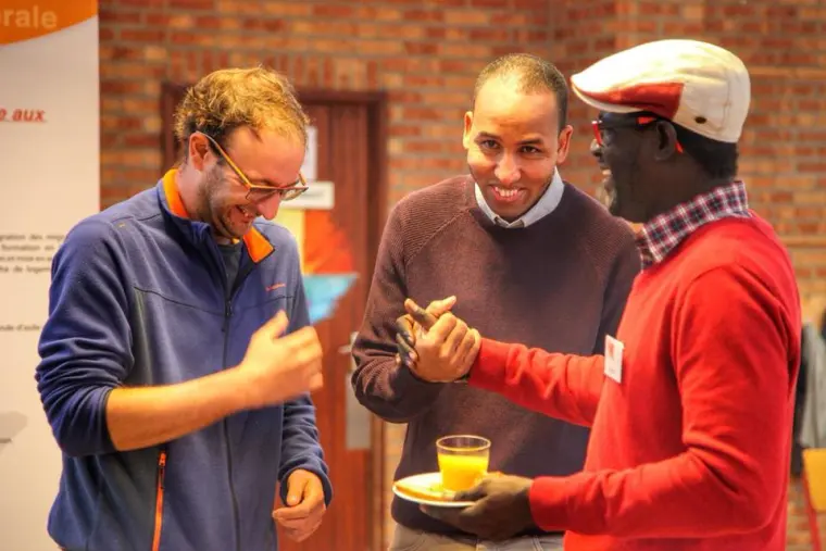 Trois hommes échangent, un verre à la main.