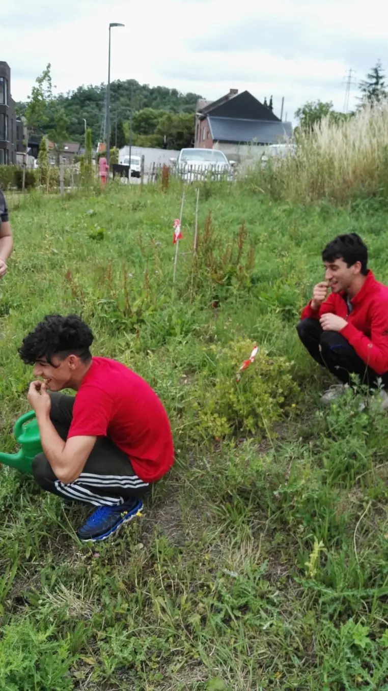 Deux jeunes accroupis dans un terrain herbeux, avant la mise en culture.