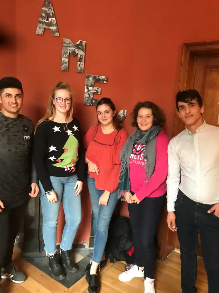 Un groupe de jeunes posent devant un mur orange.