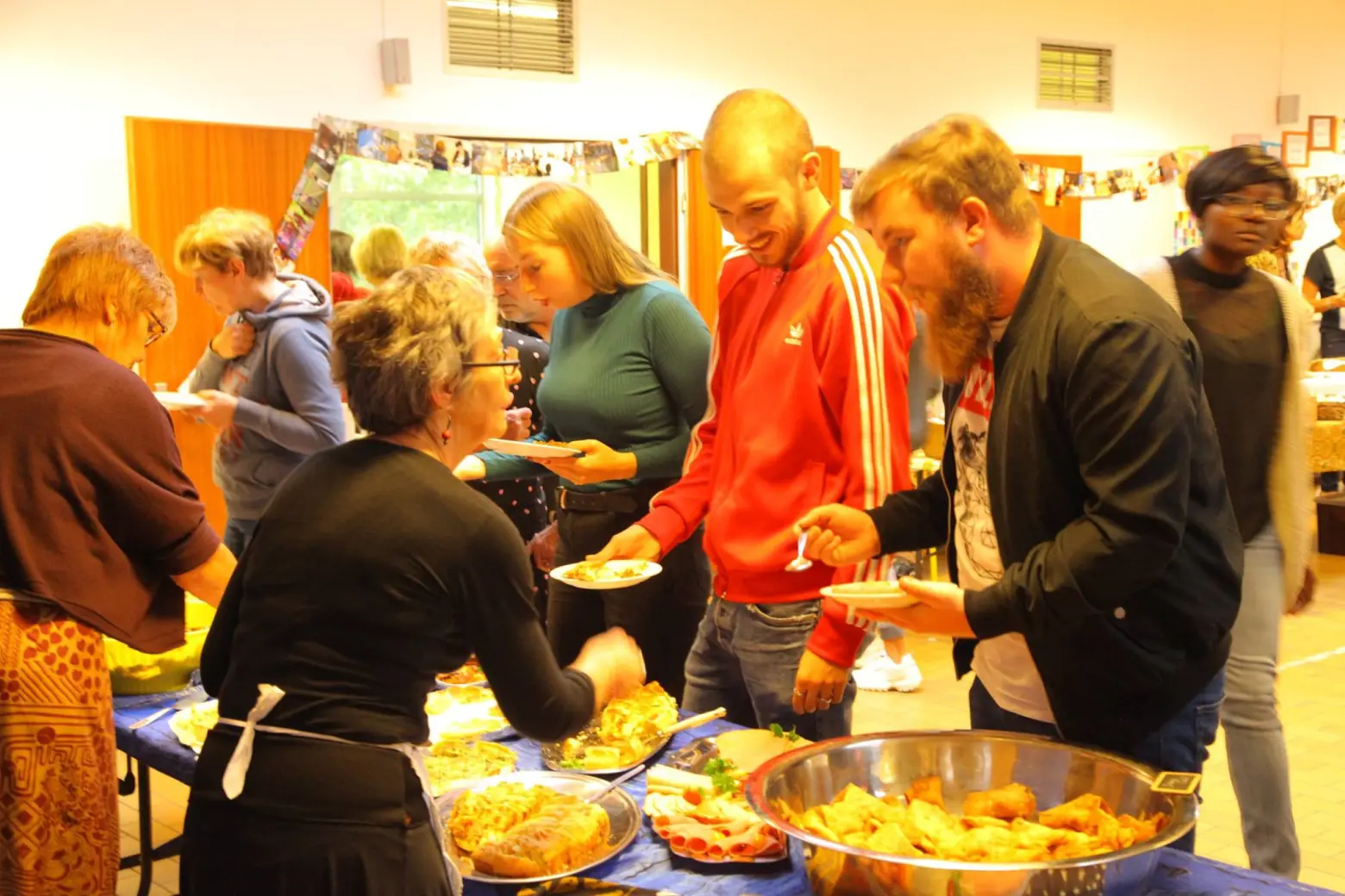 Des convives se servent au buffet, plusieurs plats devant eux.