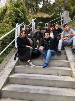 Un groupe de jeunes assis dans un escalier extérieur, pendant une pause.