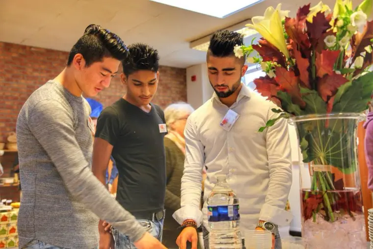 Trois jeunes hommes réunis près d'un bouquet, pendant une réception.
